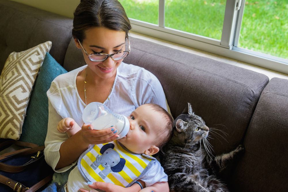 Allergic Mom Bottle Feeding Son Alongside Pet Cat